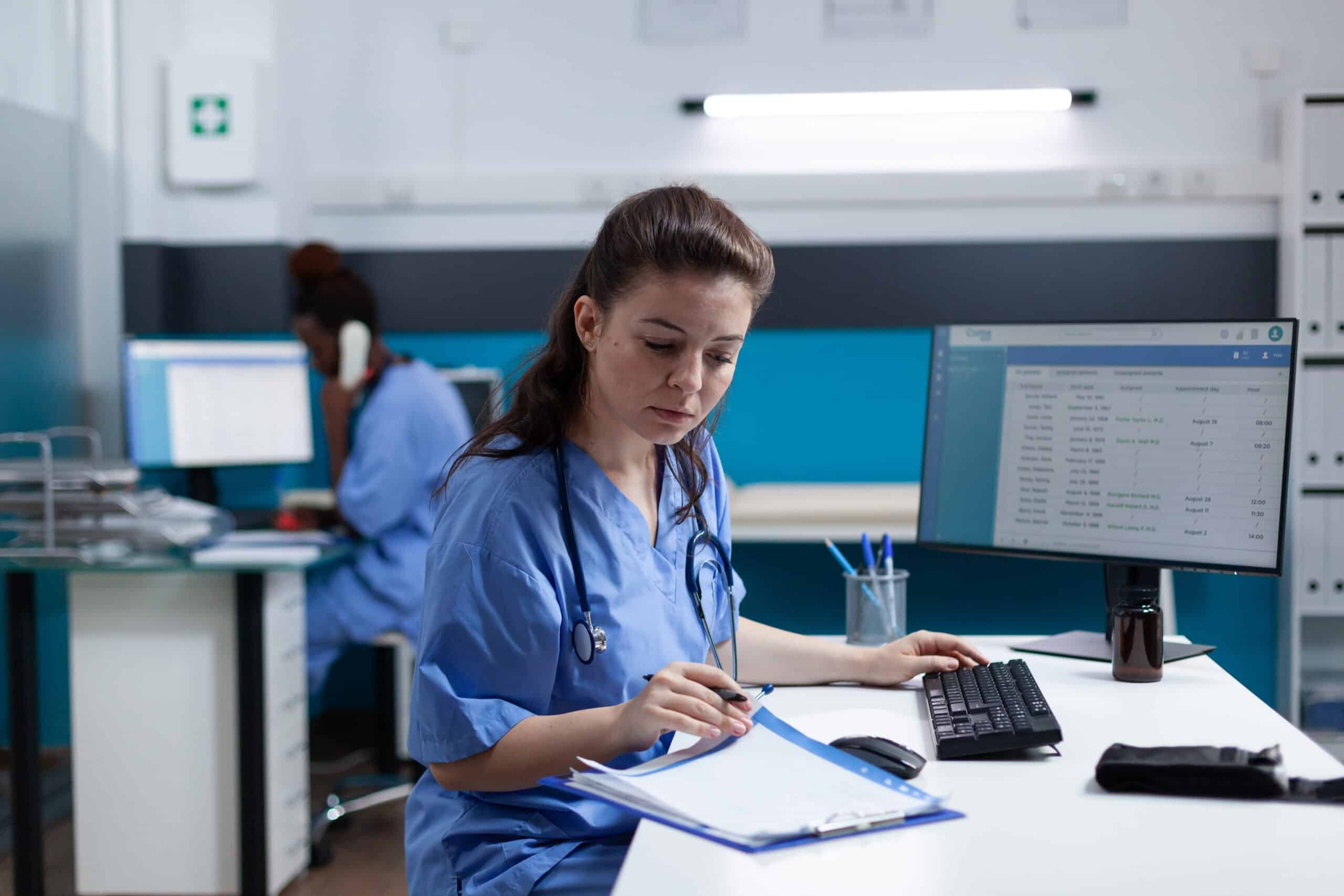 Profesional de la salud revisando documentación clínica junto a un computador